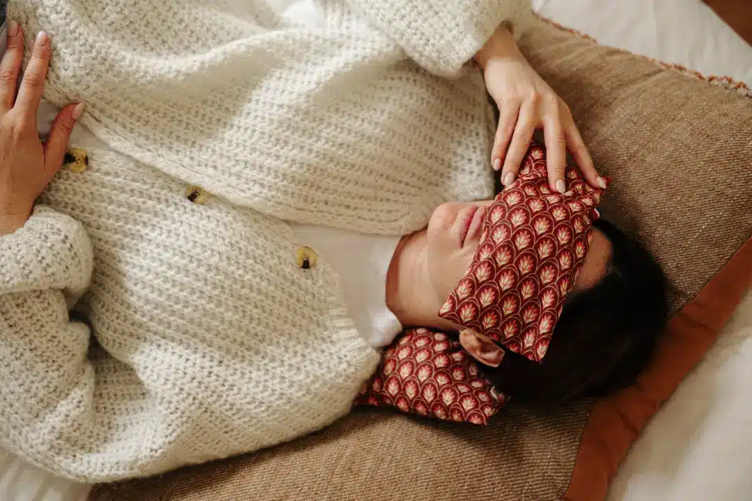 Jeune femme allongée avec un bandeau Olivotte sur les yeux et un coussin Olivotte sous la nuque